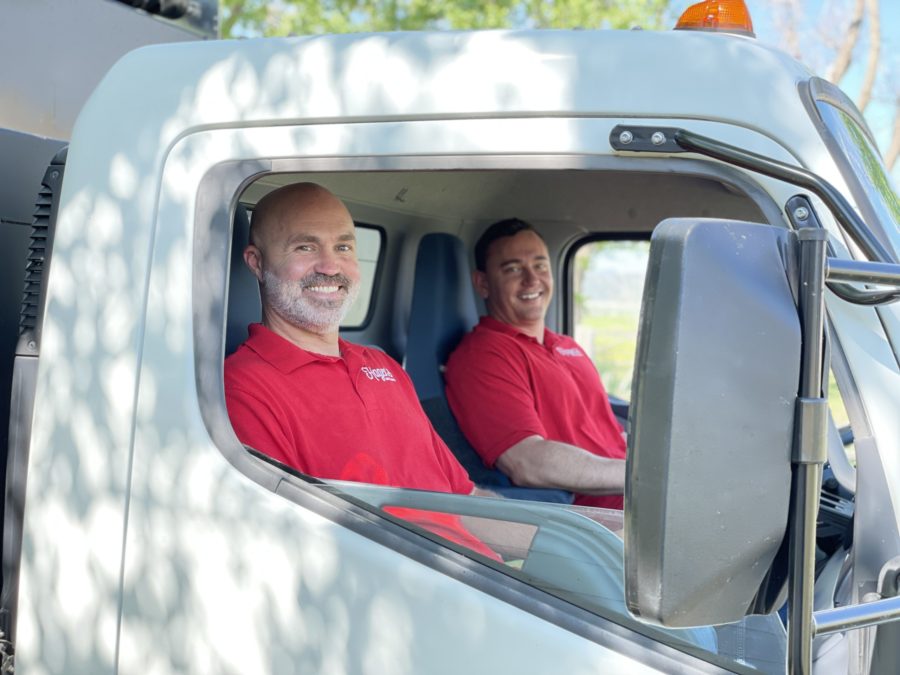 junk removal pros smiling inside of truck