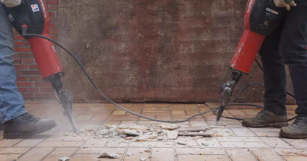 A person using a jackhammer to drill a hole in the ground 