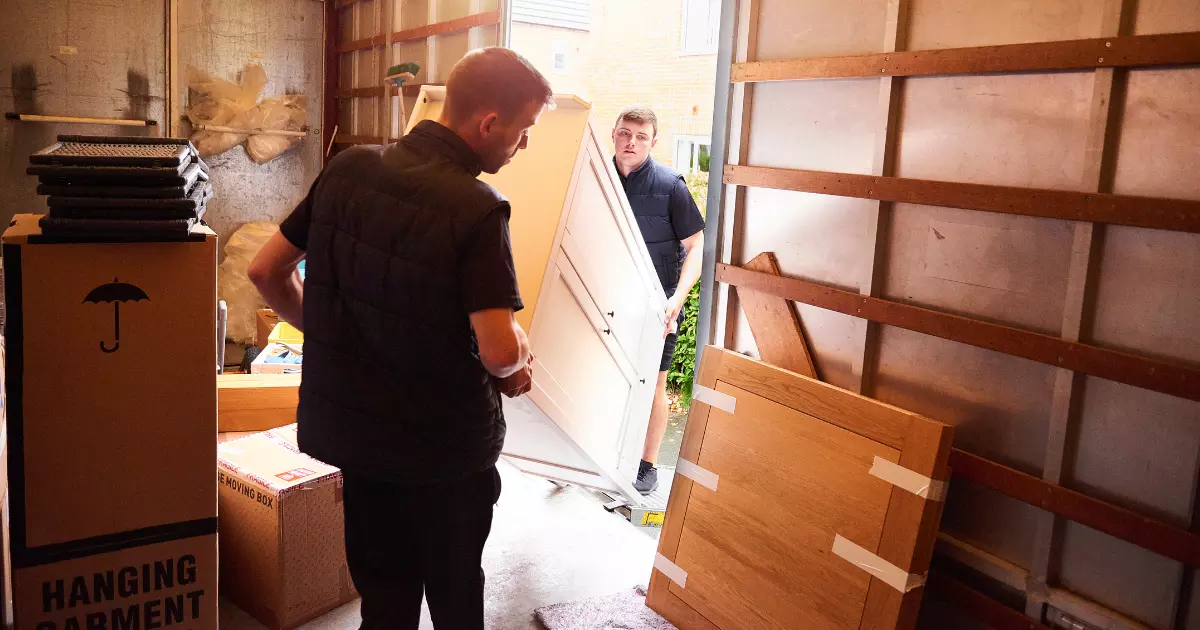 A couple of men carrying a large dresser
