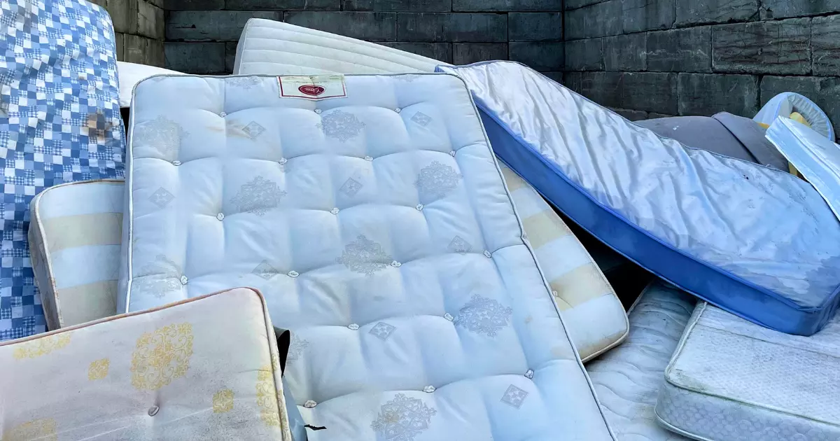 Old mattresses stacked together for mattress removal and disposal 1