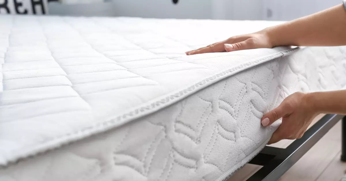 Person lifting a mattress from a bed frame during a mattress removal process 1